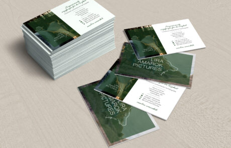 Bild: Ein Stapel Visitenkarten, sowie 4 ausgefächerte Visitenkarten zeigen je die Vor- und Rückseite der Visitenkarten für eine Tierfotografin. Die Rückseite zeigt ein randlos platziertes atmosphärisches Foto aus ihrer Hand in Vollfarbe hinter einem kleineren leicht transparentem Kasten aus dunklem Grün der dem in weiß gehaltenen Logo einen Platz bietet. Das Logo wirkt wie in das Bild geschnitten. Auf der Vorderseite befindet sich das Logo in kleiner auf einem weiteren Bild aus den Daten der Fotografin, ein Großteil der Seite ist jedoch klar weiß hinterlegt und listet die notwendigen Kontaktdaten nebst handschriftlichem Slogan "Herzensmomente, eingefangen für die Ewigkeit" auf.