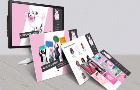 Bild: Ein 3D-gerenderter PC-Bildschirm der die Webseite der Wollmilchsäue zeigt. Das Webdesign steht jedoch noch in einzelnen Auszügen wie auf Karton gedruckt anlehnend vor dem Bildschirm und zeigt weitere Impressionen der farblich frischen Webseite.