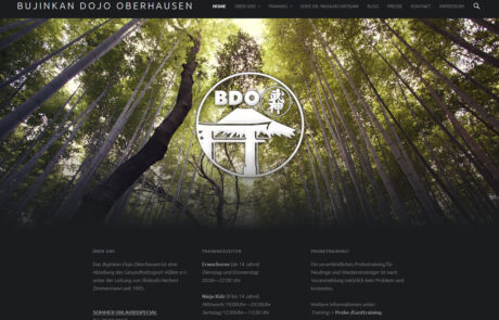 Screenshot: Eine in dunklem anthrazit gehaltene Webseite mit schlichtem Headerbalken oberhalb eines großformatigen Bildes das den Blick nach oben zu den Baumwipfeln eines Bambuswaldes zeigt, sowie das Logo des Bujinkan Dojo's Oberhausen einfarbig in Weiß. Das Bild verläuft sanft zurück in den anthrazitfarbenen Hintergrund auf dem sich die Seiteninhalte befinden.